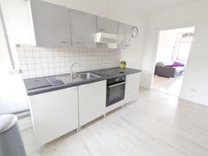 biała kuchnia ze zlewem i kuchenką w obiekcie Cosy one bed room flat at walking distance of Lux border 