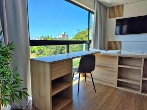 een bureau met een stoel in een kamer met een raam bij CURTA! |165| Lindo Studio | Próx Centro de Eventos in Balneário Camboriú