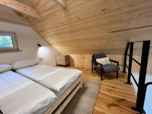 een slaapkamer met een groot bed en een stoel bij Whispering Woods Cabin in Milicz