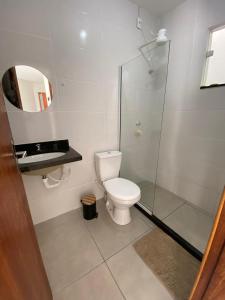 a bathroom with a toilet and a glass shower at Apartamento do Peró in Cabo Frio +11 photos