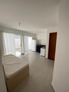 a white room with a bed and a kitchen at Apartamento do Peró in Cabo Frio