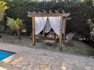 a gazebo with chairs and a table next to a pool at Fernando e Fernanda in Itupeva