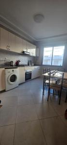 uma cozinha com uma máquina de lavar roupa, uma mesa e cadeiras em luxury apartment DT2 em Mohammedia