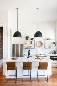 a kitchen with a large white island with chairs at East Main Your Merry Modern Downtown Getaway in Bowling Green