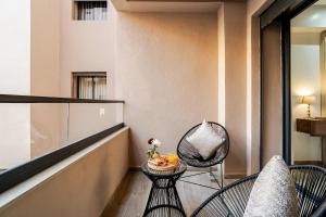 a balcony with two chairs and a bowl of fruit on a table at Appartement Moderne Poolside Gueliz centre Sun PS4 & Wi-Fi in Marrakesh