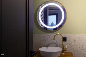 a bathroom with a sink and a round mirror at Casa Sunetul Padurii din Belis Apuseni in Finciu