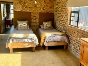 two beds in a room with a brick wall at De Krantz 6 Estate in Clarens