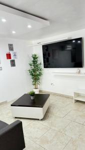 a living room with a black and white couch and a tv at Red House - Modern 2BR Near isla verde & Airport in Carolina +5 photos