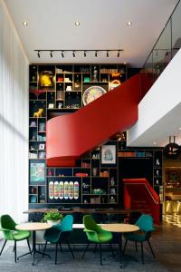a restaurant with tables and green chairs and a staircase at citizenM Washington DC Capitol in Washington, D.C.