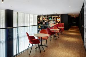 a restaurant with red chairs and tables and windows at citizenM Washington DC Capitol in Washington, D.C. +49 photos