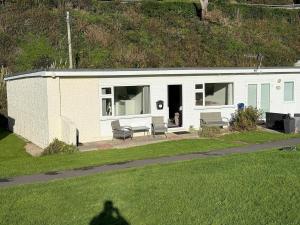 a small white house with a person standing in the grass at Seagulls Rest in Isle of Wight