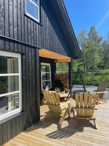 a group of chairs sitting on a deck next to a building at Modern Cabin By Hardangervidda in Garden