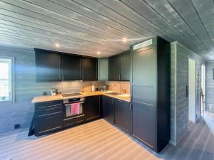 a kitchen with black cabinets and a wooden floor at Modern Cabin By Hardangervidda in Garden +24 photos
