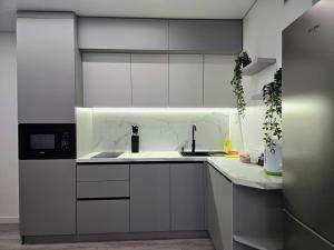 eine weiße Küche mit weißen Schränken und einer Spüle in der Unterkunft Belvedere Apart 2, parking in Iwano-Frankiwsk