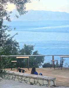 Zwei Personen liegen auf einer Terrasse und schauen aufs Meer. in der Unterkunft Cimarte The Path Lukove in Lukova