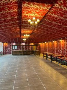 a large room with red walls and wooden tables at Spirit of the Badia camp in Disah +37 photos