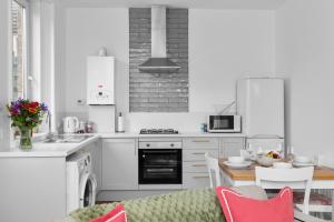 een keuken met witte kasten en een tafel met een bank bij 92 High Street in Carnoustie