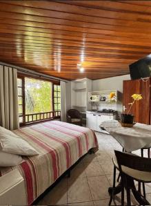 a bedroom with a bed and a table and a kitchen at Pousada Residencial dos Corais in Bombinhas