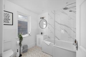 een witte badkamer met een bad en een wastafel bij 92 High Street in Carnoustie