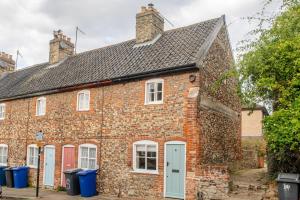an old brick house with red doors and windows at Charming Georgian flint cottage in Bury Saint Edmunds