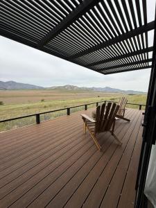 zwei Stühle auf einem Holzdeck mit Aussicht in der Unterkunft Finca Ocho Cerros in Tornquist