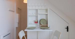 a white kitchen with a table and chairs at Le Perchoir du marché - Appartement pour 2 personnes in Saint-Nazaire