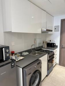 a kitchen with a washing machine and a sink at Beautiful studio at aljada community in Sharjah