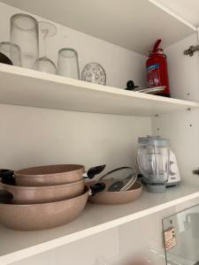 a kitchen shelf with bowls and other kitchen utensils at Beautiful studio at aljada community in Sharjah +5 photos