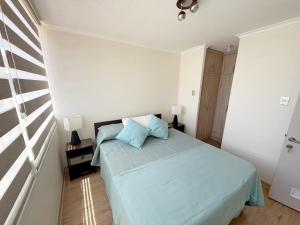 Un dormitorio con una cama con sábanas azules y una ventana. en Jardines del Pacífico IV, en La Serena 68 fotos más