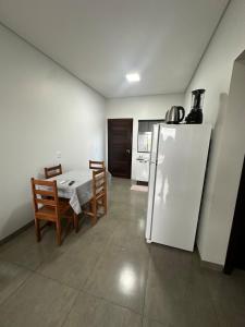 Una cocina con un refrigerador blanco y una mesa y sillas. en Casa vaga 2 carros ou caminhonete, 2 quartos, espaçosa, completa para 8 pessoas, en Sinop