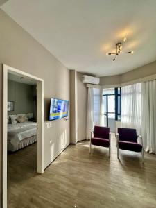 福塔莱萨1155 golden 55m2 1 quarto frente mar avenida beira mar的一间卧室配有一张床、两把椅子和一台电视