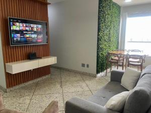 Beautiful apartment in Vila da Serra في نوفا ليما: غرفة معيشة مع أريكة وتلفزيون على الحائط