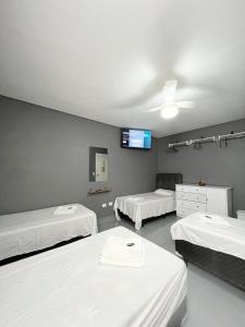 Una habitación con tres camas y un televisor en la pared. en Hostel Anprado #12, en Guarulhos