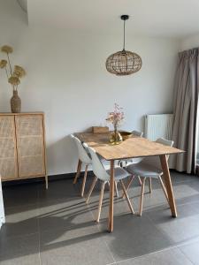 a dining room table with chairs and a vase of flowers on it at Zanderover in Koksijde