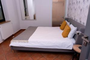 a bedroom with a bed with white sheets and yellow pillows at Mały Domek w Górach Sowich in Pieszyce