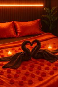 two swans forming a heart on a bed with candles at Suite Romantique avec balnéothérapie double & sauna Privés - Nuit s'exception in Briord