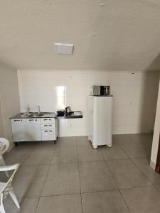 an empty kitchen with a refrigerator and a sink at Loft do Valle II in Sorriso