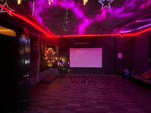Una habitación con luces violetas y una pantalla blanca. en Dim delights, en Nueva Delhi