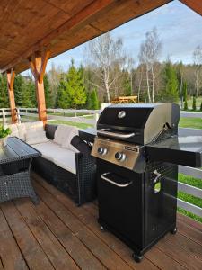 ein Grill auf einer Terrasse mit Sofa und Tisch in der Unterkunft Bieszczadzka Perełka in Równia