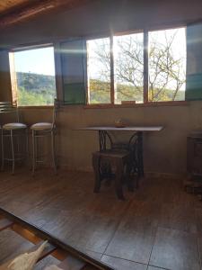 Una mesa y sillas en una habitación con ventanas. en Pie de Sierra, en Los Hornillos