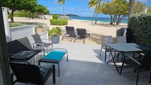 a patio with chairs and tables and a beach at Tekila Beach, appt-condo au bord de mer a Saint-Martin SXM in Baie Nettle