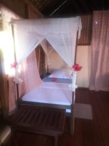 een slaapkamer met een hemelbed en witte gordijnen bij Antafondro Lodge in Sainte Marie