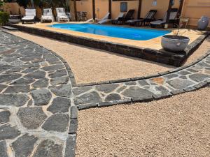 una piscina con sentiero in pietra accanto a una casa di Jolie Villa Santa avec piscine a Pointe-aux-Piments