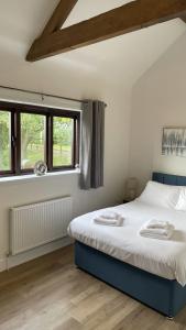 a bedroom with two beds and two windows at Eastfields Farm Barns in Melchbourne