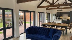 a living room with a blue couch and a table at Eastfields Farm Barns in Melchbourne