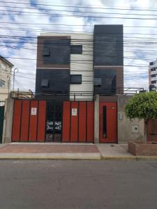 a building with orange and black doors on a street at Cuarto acogedor independiente in Cochabamba