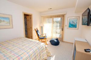 a bedroom with a bed and a tv and a chair at Soundside-Resort Amenities, Comm Pool-322, Out of Bounds in Corolla
