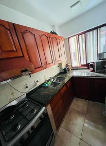 Una cocina con gabinetes de madera y un horno de estufa. en Dpto a pasos de la peatonal, en Villa Carlos Paz