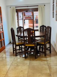 mesa de comedor de madera y sillas con ventana en Dpto a pasos de la peatonal, en Villa Carlos Paz 1 foto más
