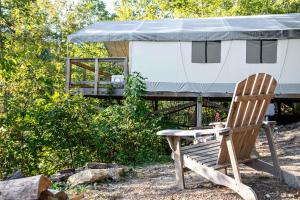 a wooden chair sitting in front of a yurt at The Goldfinch's Nest - Glamping Tent with AC in Rogers